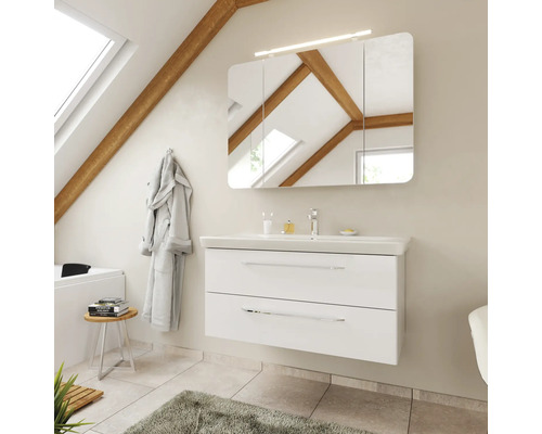 Salle de bains moderne avec meuble sous-lavabo blanc, deux tiroirs, lavabo en céramique et armoire de toilette LED sous un toit incliné.