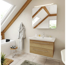 Salle de bains moderne sous les combles avec meuble sous vasque aspect chêne, lavabo blanc et armoire de toilette éclairée.