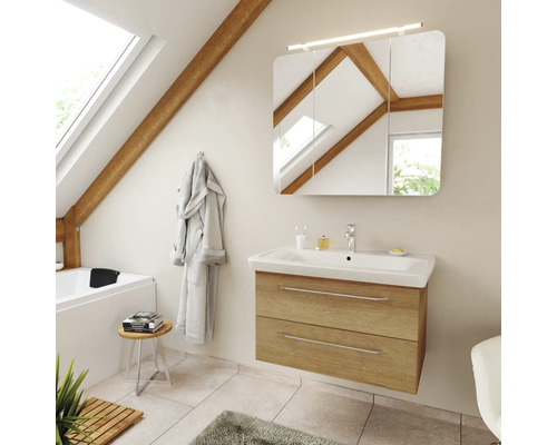 Salle de bains moderne sous les combles avec meuble sous vasque aspect chêne, lavabo blanc et armoire de toilette éclairée.