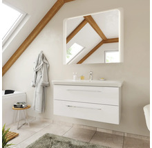 Meuble sous-vasque blanc avec lavabo et miroir éclairé dans une salle de bains lumineuse avec plafond incliné et poutres en bois.