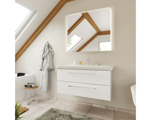 Meuble sous-vasque blanc avec lavabo et miroir éclairé dans une salle de bains lumineuse avec plafond incliné et poutres en bois.
