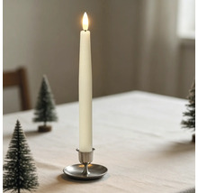 LED-Stabkerze in einem Metallhalter auf einem hell gedeckten Tisch mit kleinen Deko-Weihnachtsbäumen.