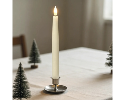 LED-Stabkerze in einem Metallhalter auf einem hell gedeckten Tisch mit kleinen Deko-Weihnachtsbäumen.
