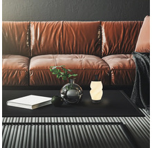 Moderne Wohnzimmerszene mit einer leuchtenden, spiralförmigen LED-Dekoleuchte auf einem schwarzen Couchtisch vor einem braunen Ledersofa.