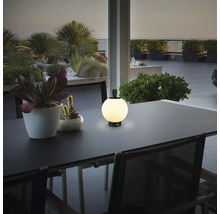 Tragbare LED-Außenleuchte auf einem Tisch, kugelförmig mit gerippter Oberfläche, in einer modernen Terrassenumgebung mit Pflanzen.