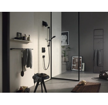 Salle de bains moderne avec douche noire, paroi en verre à cadre noir, porte-serviettes et tapis de bain en bois.