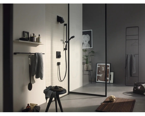 Salle de bains moderne avec douche noire, paroi en verre à cadre noir, porte-serviettes et tapis de bain en bois.