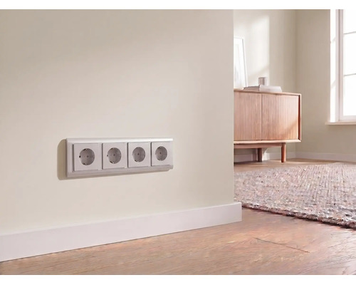 Prise électrique quadruple installée sur un mur au-dessus d'une plinthe dans une pièce moderne et lumineuse.