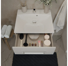 Meuble sous-vasque moderne avec vasque et tiroir ouvert contenant des accessoires de salle de bain à côté d'un tabouret avec serviettes.