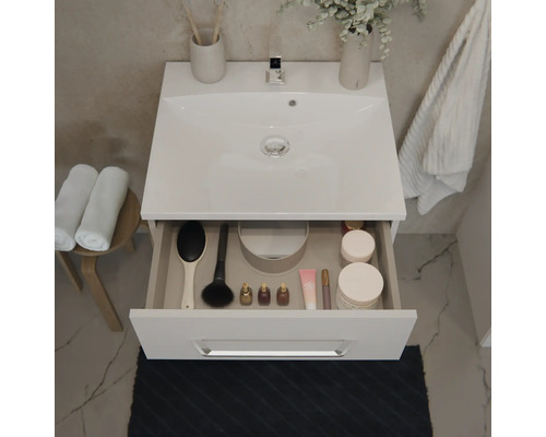 Meuble sous-vasque moderne avec vasque et tiroir ouvert contenant des accessoires de salle de bain à côté d'un tabouret avec serviettes.
