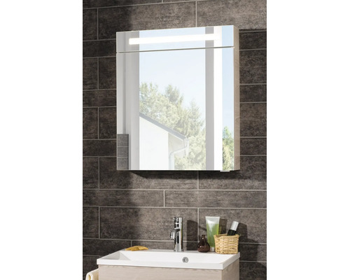 Armoire de toilette avec éclairage LED au-dessus d'un lavabo blanc avec robinet chromé sur un mur de carreaux foncés texturés.