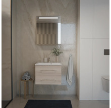 Ensemble de salle de bain moderne avec meuble sous-vasque suspendu aspect bois, lavabo blanc et miroir éclairé sur un mur aspect pierre.