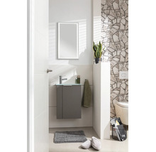 Toilettes d'invités modernes avec meuble gris sous-lavabo, vasque en verre, robinetterie chromée et miroir LED devant un mur en pierre naturelle.