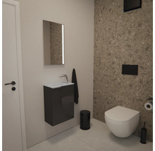 WC d'invités moderne avec WC suspendu, meuble sous-vasque gris avec petit lavabo, miroir et accessoires noirs devant un mur en pierre.