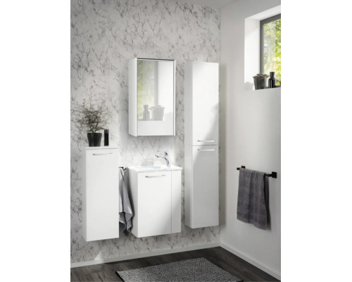 Ensemble de meubles de salle de bain blanc avec sous-vasque, armoire de toilette, colonne et meuble latéral devant un mur à motif de marbre.
