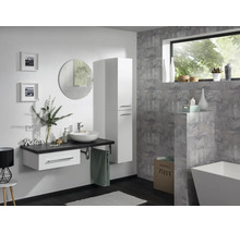 Salle de bains moderne avec meuble sous-lavabo blanc, vasque à poser, colonne, miroir rond et mur gris aspect pierre.