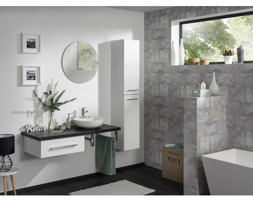 Salle de bains moderne avec meuble sous-lavabo blanc, vasque à poser, colonne, miroir rond et mur gris aspect pierre.