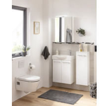 Salle de bains lumineuse avec meuble sous-lavabo blanc, WC suspendu, armoire de toilette et colonne de rangement sur sol en bois clair.