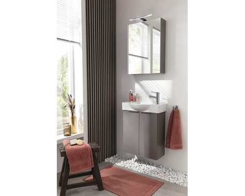Salle de bains moderne et lumineuse avec meuble sous-lavabo gris, lavabo blanc, armoire de toilette éclairée et mur en lattes de bois.