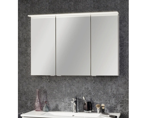 Armoire de toilette à trois portes avec éclairage sur le dessus, montée au-dessus d'un lavabo blanc.
