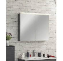 Spiegelschrank mit zwei Türen und LED-Beleuchtung an einer hellen Wand mit Steinoptik über einem Waschbecken im Badezimmer.