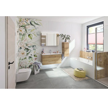 Salle de bains moderne et lumineuse avec meuble sous-lavabo aspect bois, armoire de toilette, baignoire blanche et papier peint floral.