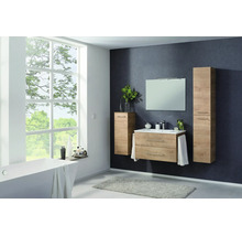 Ensemble de meubles de salle de bains moderne en aspect bois avec meuble sous-lavabo, lavabo, miroir et armoires hautes dans une pièce lumineuse.