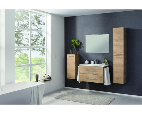 Ensemble de meubles de salle de bains moderne en aspect bois avec meuble sous-lavabo, lavabo, miroir et armoires hautes dans une pièce lumineuse.
