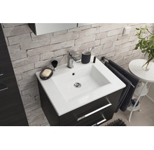 Meuble de salle de bain moderne avec vasque en céramique blanche, robinetterie chromée et meuble foncé contre un mur aspect pierre.