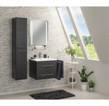 Ensemble de salle de bains moderne en bois avec meuble sous-lavabo, armoire haute et miroir éclairé sur un mur en briques.