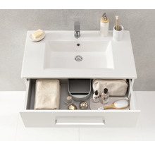 Meuble sous-vasque blanc moderne avec lavabo en céramique et un tiroir ouvert montrant un rangement organisé pour les articles de toilette.