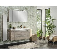 Modernes Badezimmerset mit Waschtisch in Holzoptik, weißem Waschbecken, großem Spiegelschrank und passendem Hochschrank vor Palmen-Tapete.