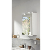 Armoire de toilette moderne à deux portes avec éclairage LED au-dessus d'un lavabo dans une salle de bains lumineuse avec carrelage mural.