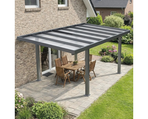 Moderne Terrassenüberdachung aus Aluminium in Anthrazit mit lichtdurchlässigem Dach auf einer gepflasterten Terrasse mit Gartenmöbeln.