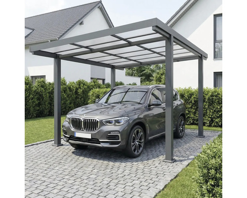 Moderner Carport aus Aluminium mit lichtdurchlässigem Dach über einem Fahrzeug auf einer gepflasterten Einfahrt neben einem Wohnhaus.