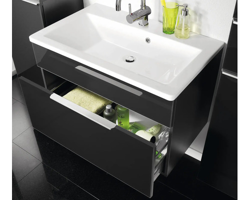 Waschtischunterschrank mit weißem Keramikwaschbecken und verchromter Armatur, eine geöffnete Schublade mit Badutensilien.