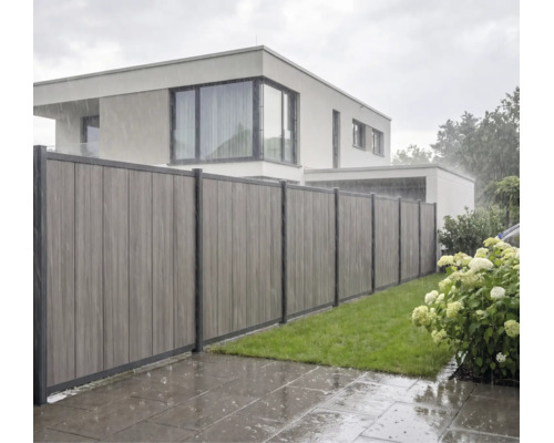 Clôture pare-vue moderne composée de panneaux verticaux en matériau composite sous la pluie dans un jardin avec pelouse.