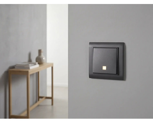 Interrupteur moderne avec voyant lumineux sur un mur gris dans une pièce au design minimaliste.