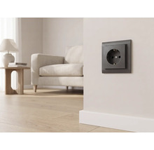 Prise de courant foncée sur un mur clair dans un salon moderne avec un canapé et un parquet.