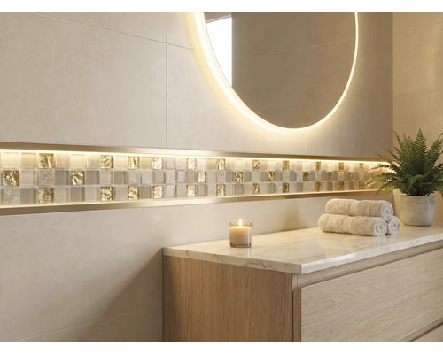Helles Badezimmer mit großformatigen Wandfliesen, einem Mosaikstreifen aus Glas und Gold mit LED Beleuchtung, einem runden Leuchtspiegel und einem Waschtisch aus Holz.