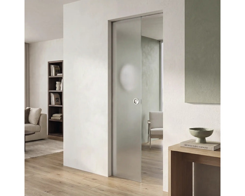 Moderne Glasschiebetür aus mattiertem Glas in einem hellen Wohnzimmer mit hellem Parkettboden und weißer Wand.