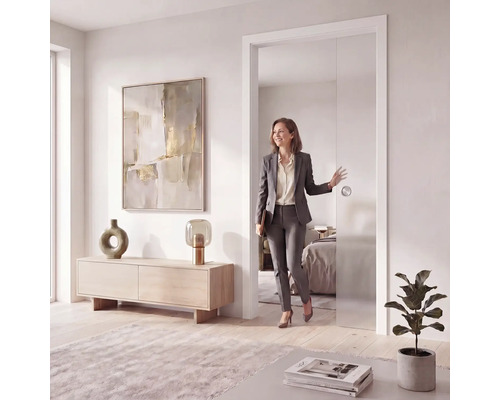 Porte coulissante moderne en verre dans un intérieur lumineux, design sans cadre avec poignée ronde, femme passant par la porte ouverte.