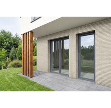 Fassade mat hellen Verblendsteine mat Klinkeroptik, gliesene Fronten an enger Terrass mat groe Steenplacken.