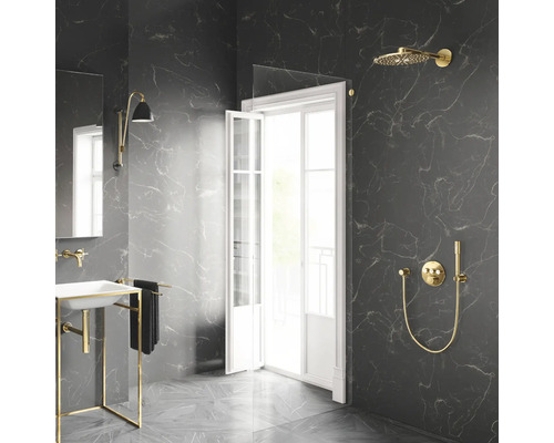 Salle de bains moderne avec carrelage en marbre foncé, robinetterie de douche dorée, paroi en verre et lavabo blanc sur cadre doré.