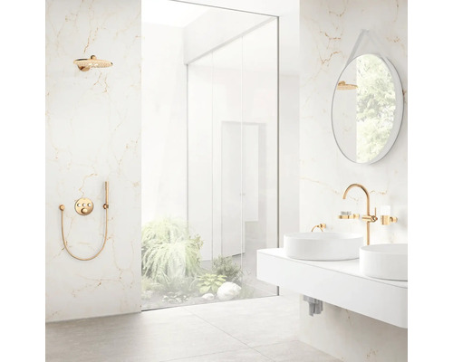 Modernes helles Badezimmer mit Marmoroptik-Fliesen, Doppelwaschtisch mit goldenen Armaturen und begehbarer Dusche mit Blick auf Pflanzen.