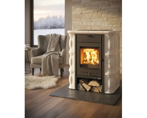 Poêle à bois avec carreaux de céramique et feu brûlant dans un salon lumineux avec fauteuil, couverture et tapis.