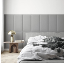 Modernes Schlafzimmer mit rechteckigen, gepolsterten Wandpaneelen, einem Bett mit weißer Bettwäsche und einem Beistelltisch mit goldener Lampe.