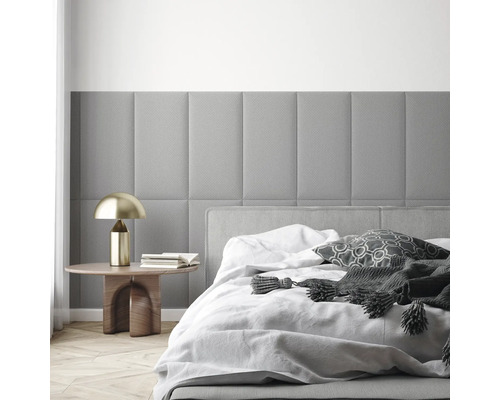 Modernes Schlafzimmer mit rechteckigen, gepolsterten Wandpaneelen, einem Bett mit weißer Bettwäsche und einem Beistelltisch mit goldener Lampe.