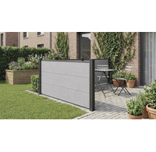 Moderner Sichtschutzzaun in Betonoptik auf einer gepflasterten Terrasse neben einer Rasenfläche mit Sitzgruppe und bepflanzter Ziegelwand.
