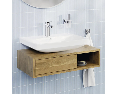 Salle de bain lumineuse avec une vasque à poser blanche sur un meuble sous-vasque suspendu en bois avec tiroir et étagère ouverte.